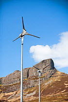 Wind turbines beneath An Sgurr, Isle of Eigg. Isle of Eigg produces all the energy the island needs from renewable energy. Eigg, Scotland, UK, May.