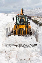 JCB clearing a way through massive snow drifts blocking the Kirkstone Pass road above Ambleside,Lake District, UK. March 2013