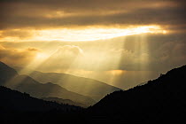 Shafts of light at dusk over Wrynose pass and the Coniston hills from Ambleside, Lake District, England, UK. September 2015