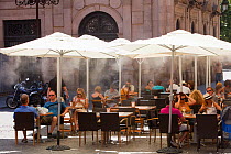 Cafe is using mist sprayers to try to cool customers down during hot weather, Seville, Andalucia, Spain, May 2011