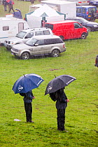 Men with umbrella  in the rain at The Vale of Rydal Sheepdog Trials, in Ambleside, Lake District, UK. August 2010