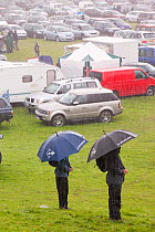 Men with umbrellas  in the rain at The Vale of Rydal Sheepdog Trials, in Ambleside, Lake District, UK. August 2010