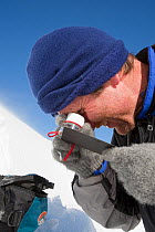 Member of the Scottish Avalanche Information Service looks at snow crystals to help assess avalanche risk on  Cairngorm in the Cairngorm National Park, Scotland, UK. March 2009