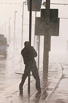 Man holding onto post during severe storm with hurricane force winds, Blackpool, England, UK, November 2007.