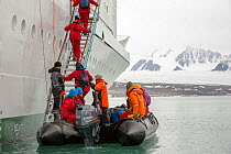 Passengers disembark Zodiaks onto the Russian research vessel, AkademiK Sergey Vavilov an ice strengthened ship on an expedition cruise to Northern Svalbard in front of a glacier. July 2013