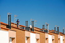 Man working on solar water heaters on a house roof in Sanlucar La Mayor in Andalucia, Spain. May 2011