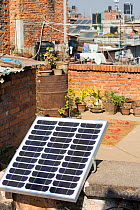 A tiny solar photo voltaic panel on a rooftop in Kathmandu, big enough to power a couple of lights in the house below, Nepal. January 2013