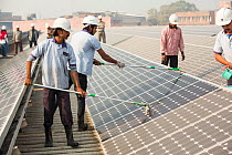Workers washing dust off solar panels at station run by Tata power on the roof of an electricity company in Delhi, India, to make them more efficient. December 2013