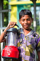 Boy holding a solar lantern, charged from the solar panelsfrom WWF project to supply renewable electricity to a remote island in the Sunderbans, Ganges, India. December 2013