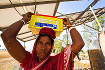 Woman collecting solar charged batteries from  WWF project to supply electricity to a remote island in the Sunderbans, Ganges Delta, India. December 2013