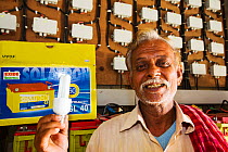 Old man with a low energy light bulb which he can use to power house with solar charged batteries from WWF project to supply electricity to a remote island in the Sunderbans, Ganges Delta, India. Dece...