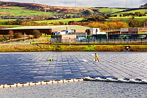 Floating solar farm being grid connected on Godley Reservoir in Hyde, Manchester, England, UK. February 2016