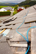 Fitting wiring to a house roof in Ambleside, Cumbria, UK, to support solar photo voltaic panels. August 2011