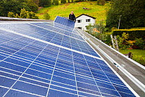 Technicians fitting solar photo voltaic panels to a house roof in Ambleside, Cumbria, UK. August 2011