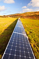 A farm house on the edge of Ilkley moor that has solar panels in the field behind the farmhouse to help power the house. West Yorkshire, UK. March 2012