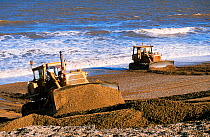 Bulldozers rebuilding the storm beach in Cley, Norfolk, England, UK.