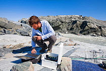 Scientist taking readings from the meltwater river at the snout of the Russell Glacier near Kangerlussuaq, Greenland. July 2008