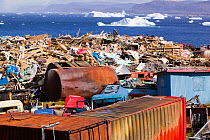 Rubbish dumped on the tundra outside Illulissat, Greenland with icebergs behind from the Sermeq Kujullaq or Illulissat Ice fjord, UNESCO World Heritage Site, Greenland. July 2008