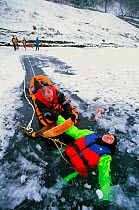 Members of the Langdale Ambleside Mountain Rescue Team rescue a man fallen through ice on Rydal Water, Lake District, England, UK.