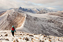 The view west into the Cuillins from Beinn na Caillich summit, behind Broadford on the Isle of Skye, Scotland, UK, with a middle aged woman walker. February 2012