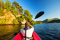 Middle aged man paddling in an inflateable kayak on Ullswater, Lake District, UK. July 2014