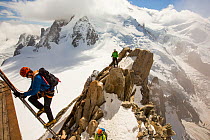 Mont Blanc with climbers on the Cosmiques Arete, climbing the ladder to access the cable car station. Aiguille Du Midi above Chamonix, France,  September 2014