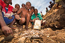 Children gathering fish, left behind by January 2015 flooding, in a hole in damaged bridge near Phalombe. Malawi, March 2015.