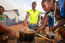 People displaced by flooding at  Chiteskesa refugee camp,  cooking on a fuel efficient stove.  near Mulanje, Malawi. March 2015.