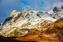 The Langdale Pikes from Blea Tarn. With a car driving over the Blea Tarn road into Little Langdale, Lake District, England, UK, January.