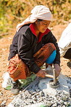 A Nepalese woman crushing stone with a hammer, Himalayan foothills, Nepal. January 2013.