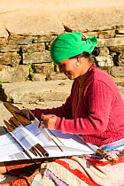 Nepalese woman in traditional clothing weaving cloth on a hand loom in the Himalayan foothills, Nepal. January 2013.