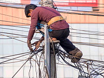 Electrician works on a tangle of electric wires in Kathmandu, Nepal. December 2012.