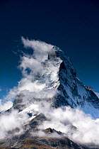 Sail clouds developing behind the lee side of the Matterhorn in the afternoon, Zermatt, Switzerland, September. The Hornli ridge is in the foreground.