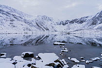 Llyn Idwal, partly frozen, with cliffs below Glyder Fawr and the Devil's Kitchen in background. Snowdonia National Park, North Wales, UK. February 2018.
