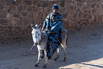 Young man wearing traditional blanket on donkey, Semonkong Lodge,  Lesotho, August 2017