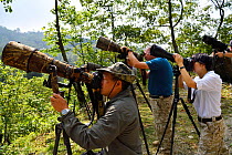 Chinese wildlife photographers looking through their cameras and taking pictures at He Xin Chang Forest reserve, Dehong Prefecture, Yunnan Province, China, May 2017.