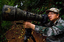Photographer Wei Jun working in the He Xin Chang Forest reserve, Dehong Prefecture, Yunnan Province, China, April.