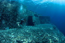 Scuba diver exploring the Yonaguni Monument, a submerged rock formation off the coast of Japan. It is unknown if these sandstone rocks are formed naturally or are of human construction, Yoguni, Japan....