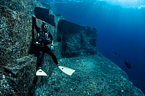 Scuba diver exploring the Yonaguni Monument, a submerged rock formation off the coast of Japan. It is unknown if these sandstone rocks are formed naturally or are of human construction, Yoguni, Japan....