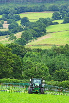 Farmer spreading slurry on organic dairy land. Slurry collected from the cattle herd is recycled as natural fertiliser, Devon, England, UK, July.