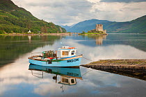 Boat in Loch Duich with Eilean Donan Castle in background, Highlands, Scotland, UK. July 2012.