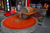 Chili mill in front of a Chili sales stands grounding chilies into powder, Old Town Muslim quarters, Xian City, Shaanxi, China, April 2018.