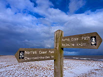 Coastal path sign at Cley Beach, under light snow, Norfolk, England, UK, February.