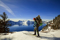 Woman cross country skiing along the north side of Rim Drive in Crater Lake National Park, Oregon, USA. March. Model released.
