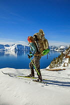 Woman cross country skiing along the north side of Rim Drive in Crater Lake National Park, Oregon, USA.  Model released.