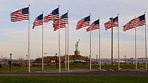 Group of American flags flying in Liberty State Park, with the Statue of Liberty in the background, New York, USA, June 2016. Hellier