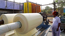Man inspecting a roller pulling fabric through a prewash bath in a textiles factory, Jaipur, Rajasthan, India, Model released, January 2018. Hellier