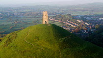 Aerial shot tracking towards St, Michael's Church Tower and Glastonbury Tor at sunrise, Somerset Levels, England, UK, October 2017. Hellier