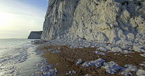 Tracking shot along the shore beneath chalk cliffs on the Jurassic Coast, Dorset, England, UK, May 2017. Hellier