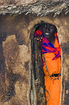 Maasai woman peering out of hut, Maasai village, Kenya. September 2006.